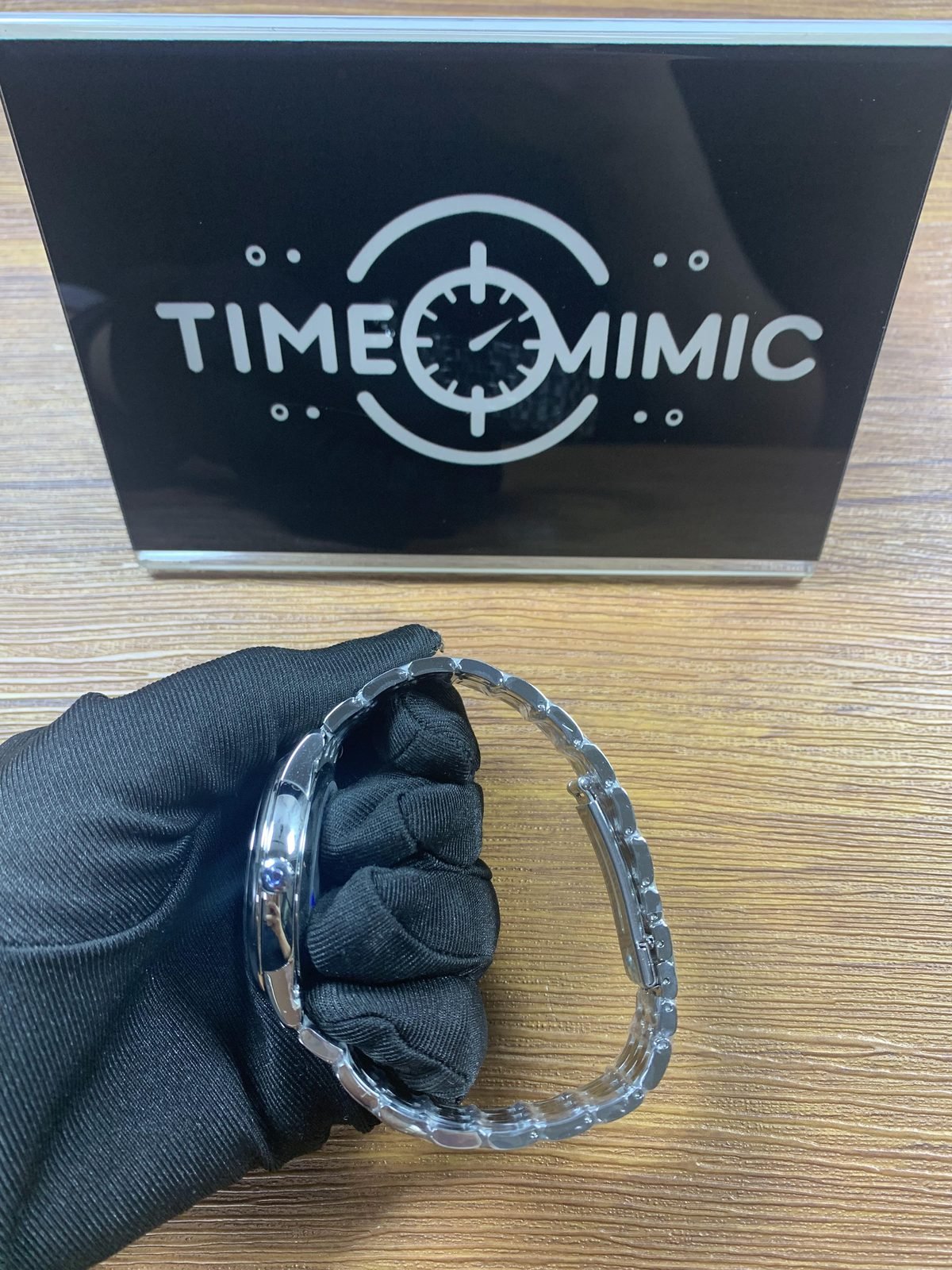 Omega De Ville replica polished crown-side case profile and steel-tone bracelet under protective film
