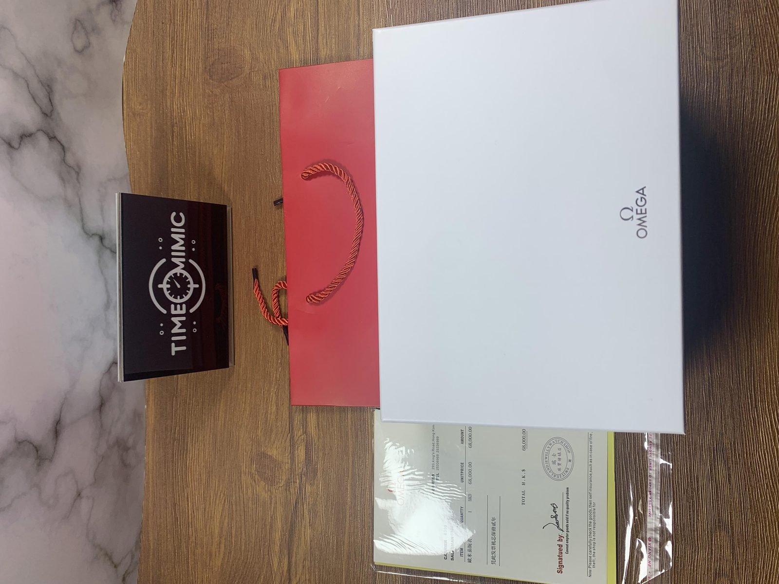 Omega De Ville replica shown beside presentation boxes red bag accessories and receipt style paper