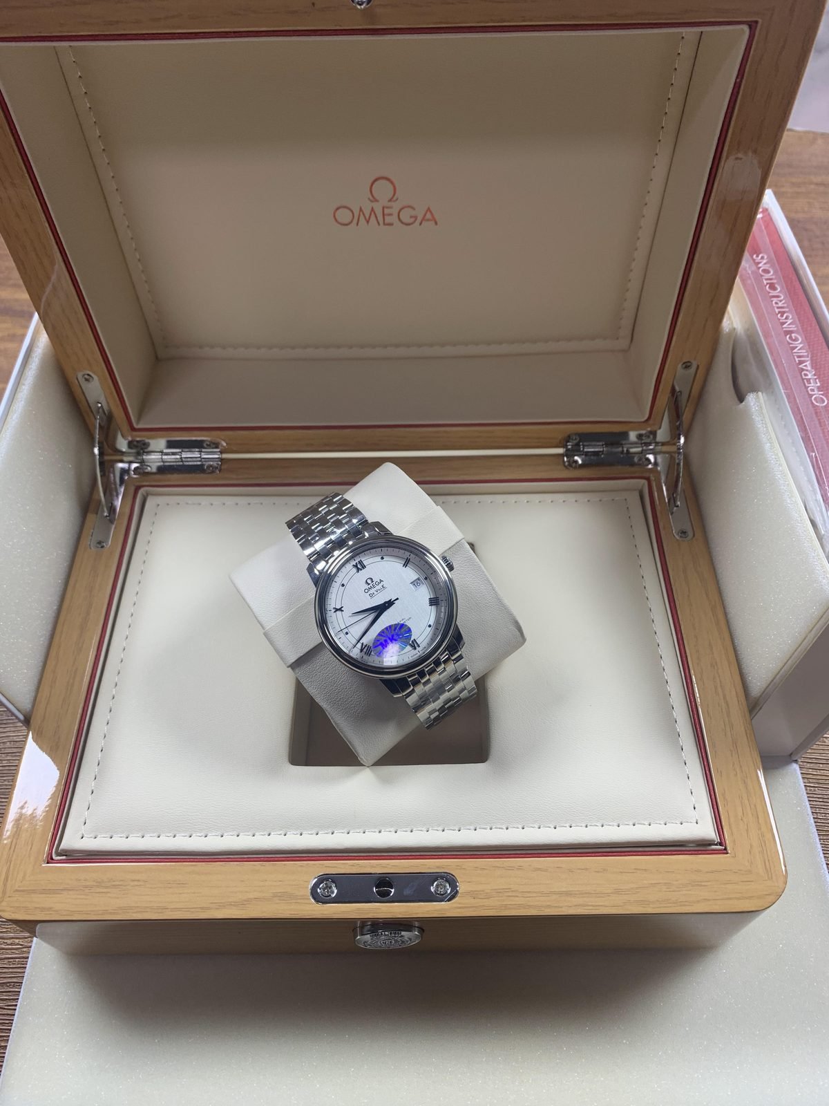 Omega De Ville replica presented in box beside instruction material