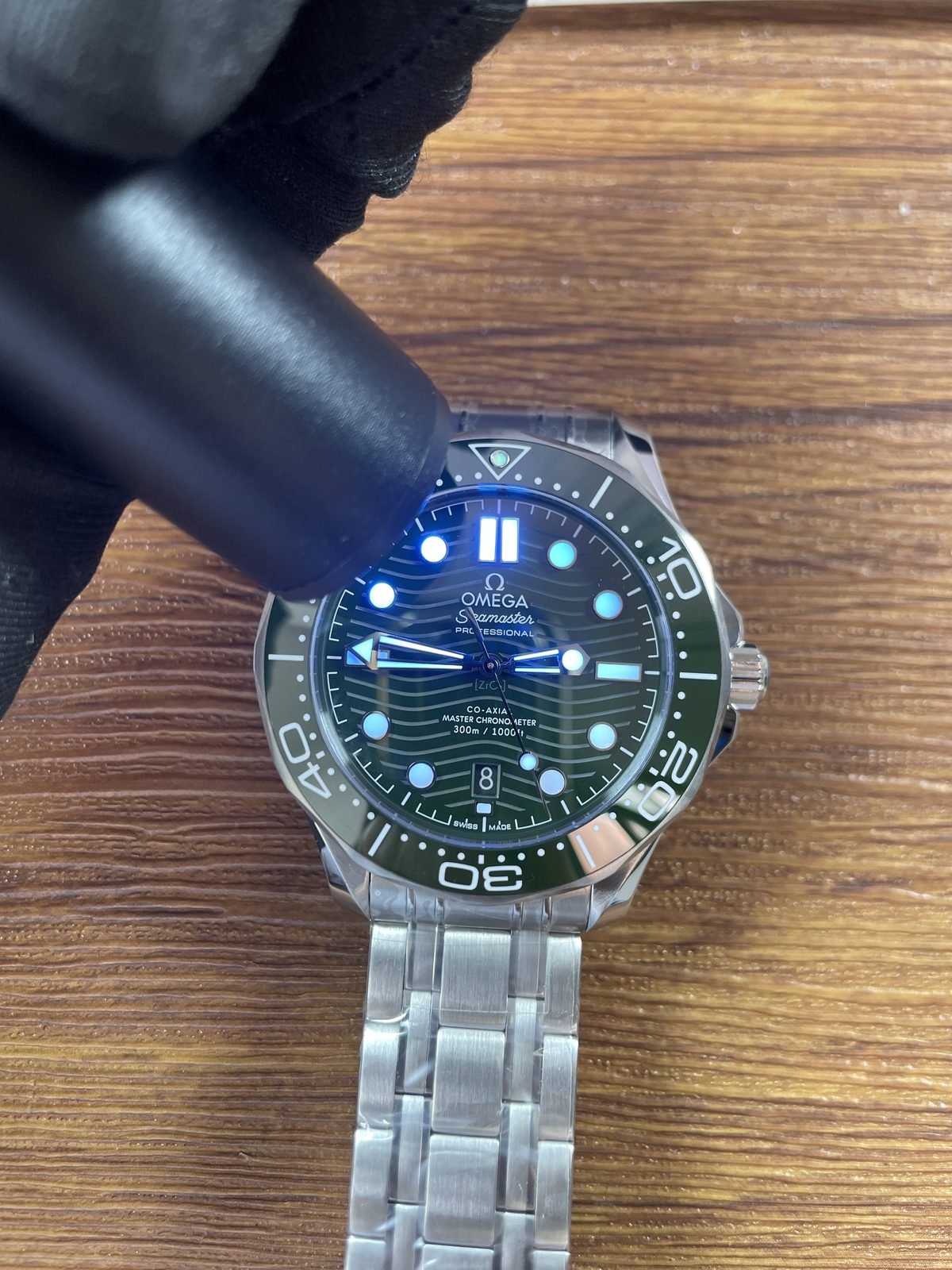 Green bezel watch under directed light showing immediate blue green luminous response
