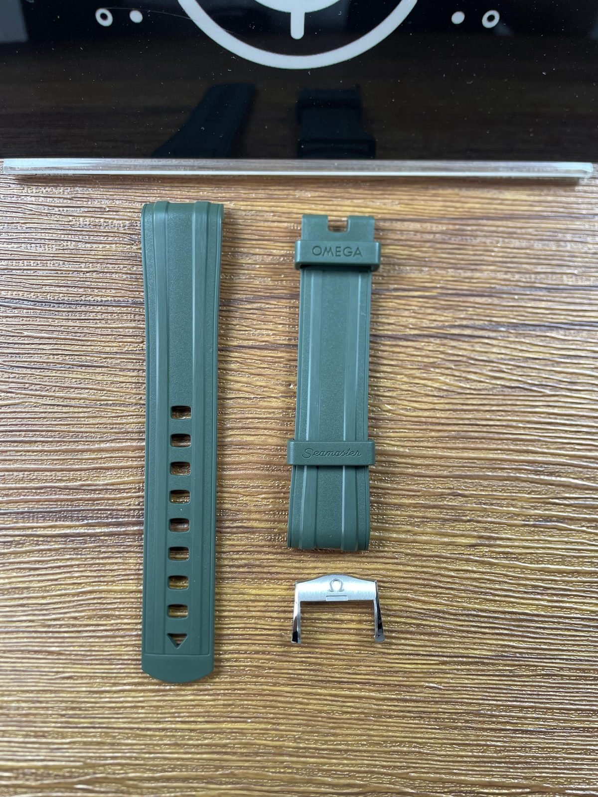 Detached green grooved strap pieces with Omega and Seamaster style moulded text plus loose metal hardware