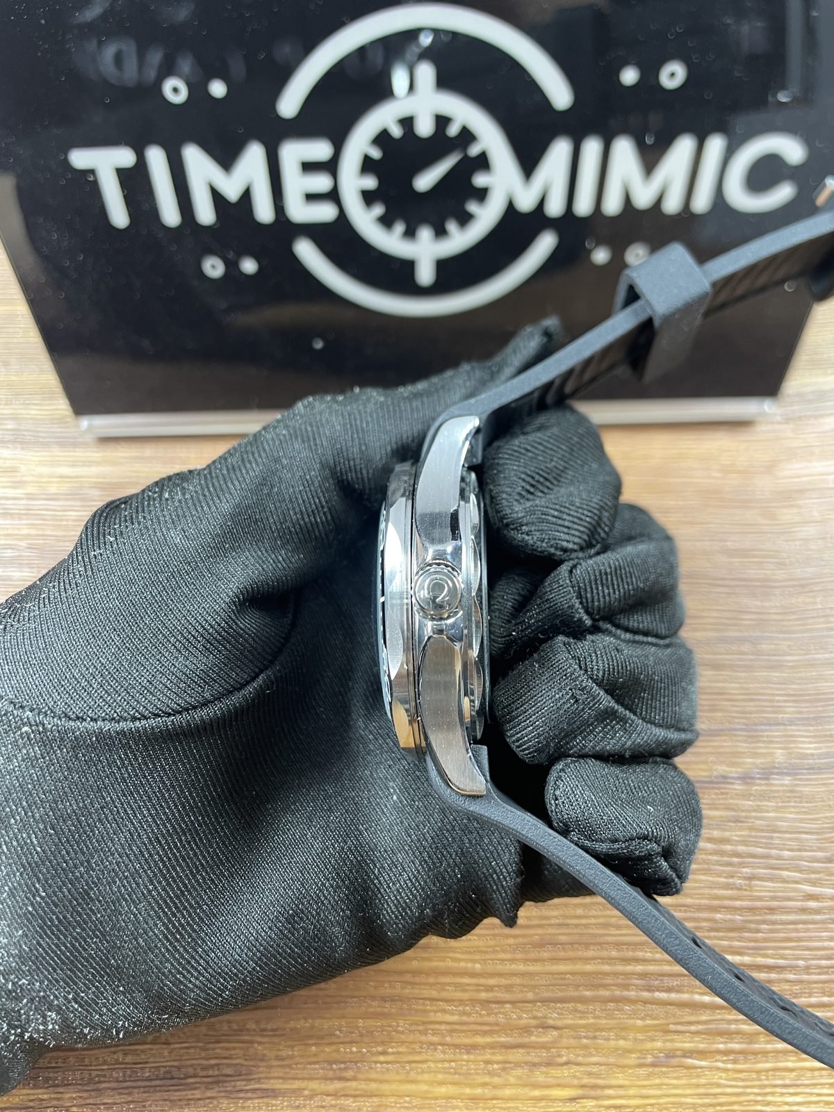 Crown side profile of black strap Seamaster style replica showing polished and brushed steel tone case