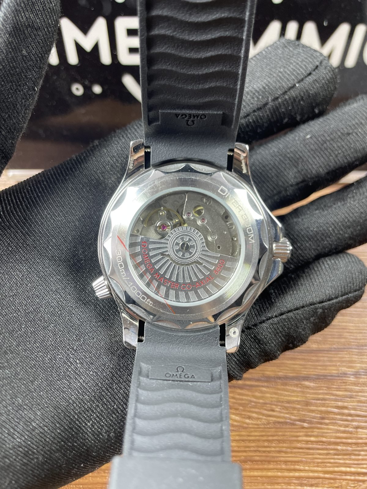 Transparent wave edged back of black strap Seamaster style replica with decorated automatic looking movement and 8800 style text