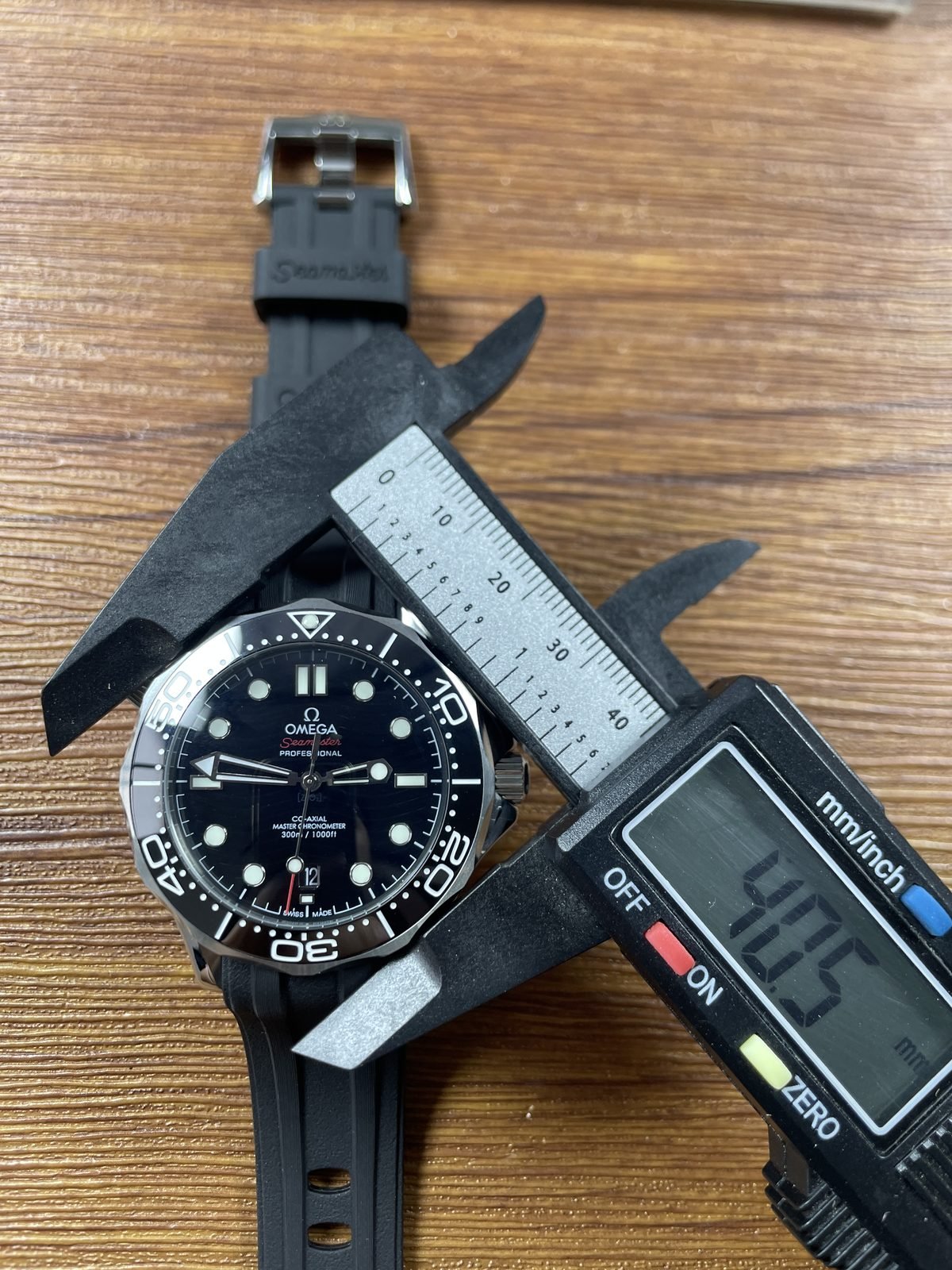 Digital calliper displaying about 50.5 millimetres across ambiguous oblique outside span of black Seamaster style replica