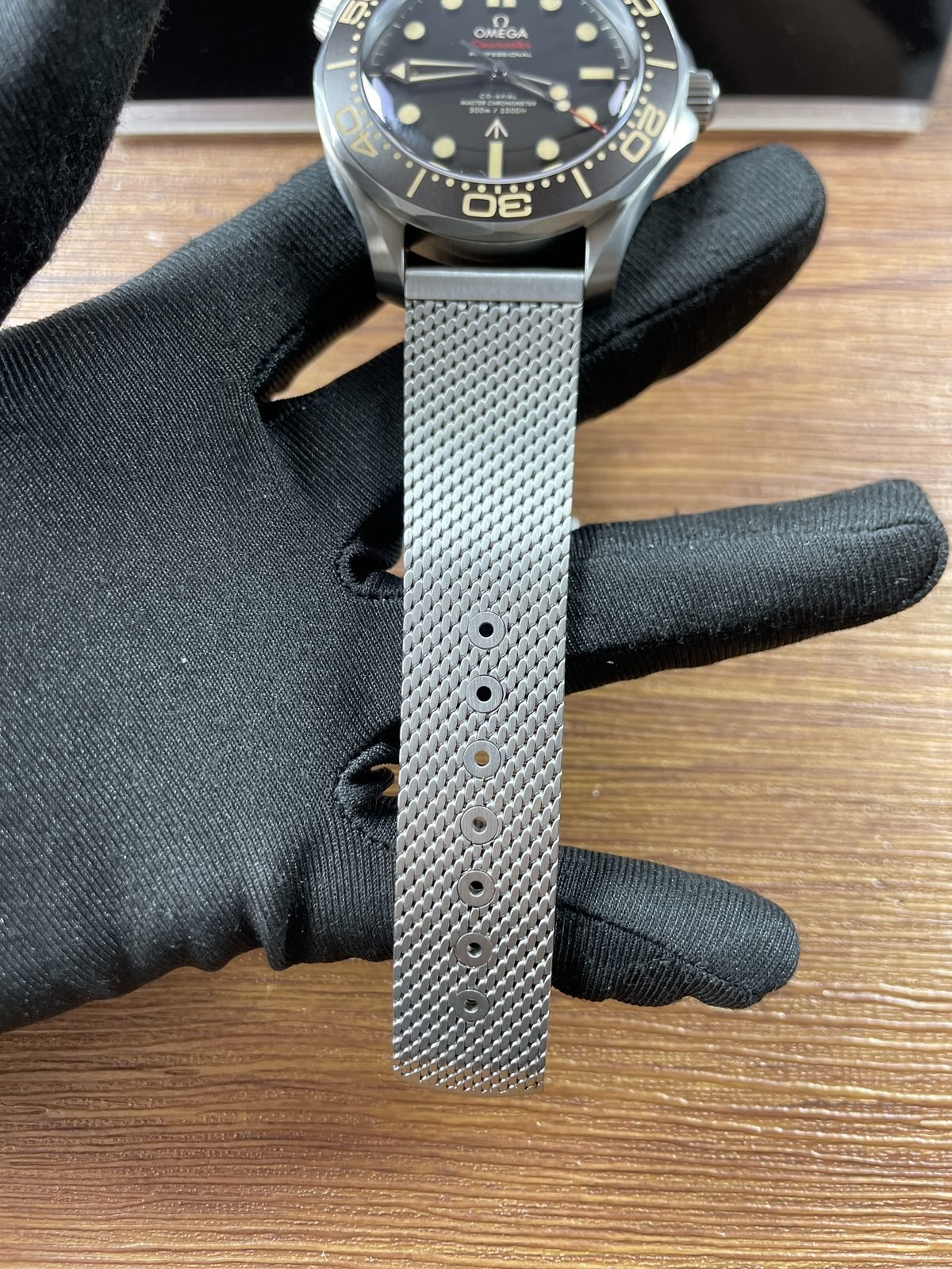 Front of no-date 007 style Seamaster replica with warm beige tone scale and mesh bracelet adjustment holes