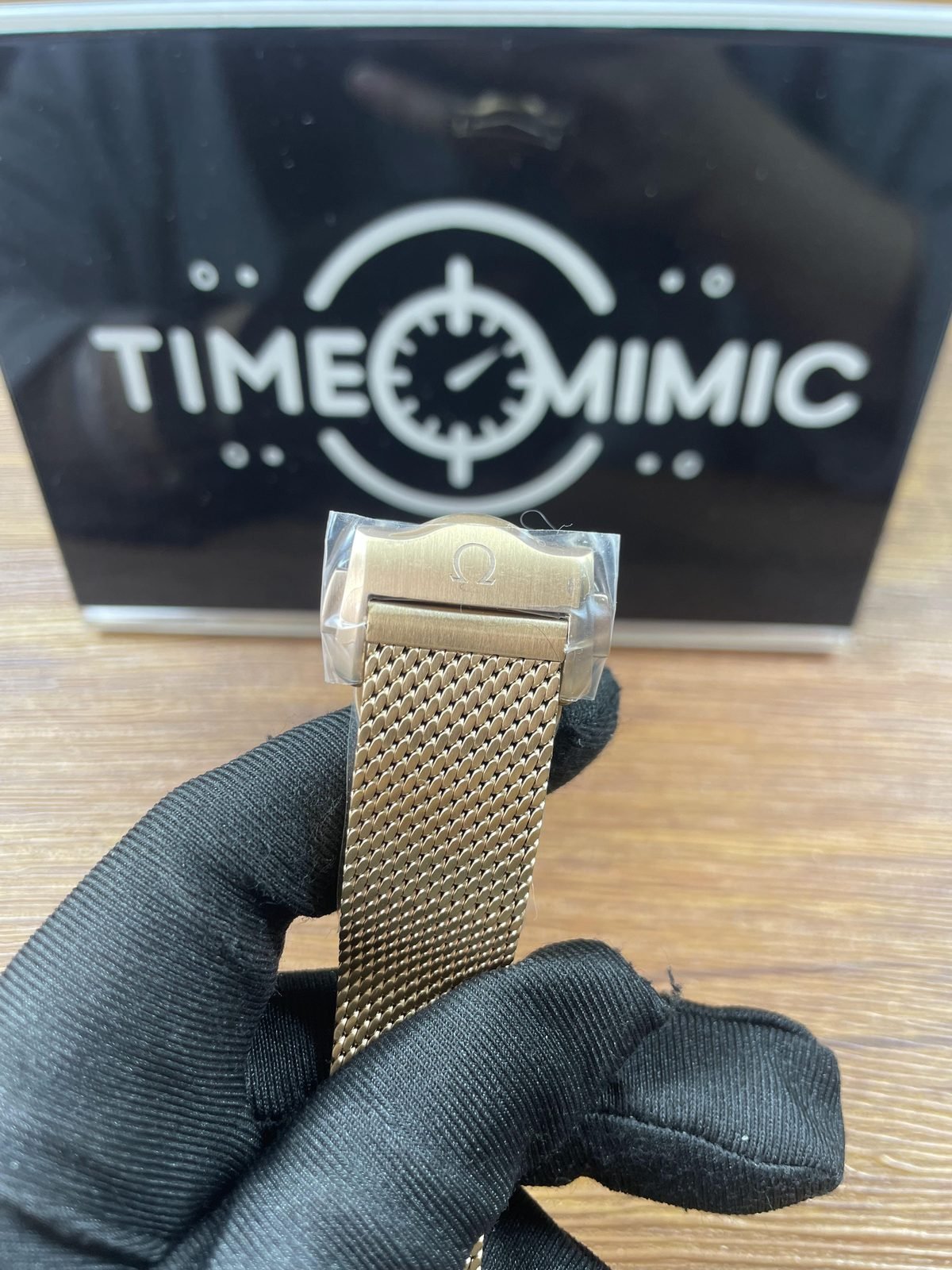 Filmed folding clasp cover with Omega style symbol and warm tone fine mesh bracelet