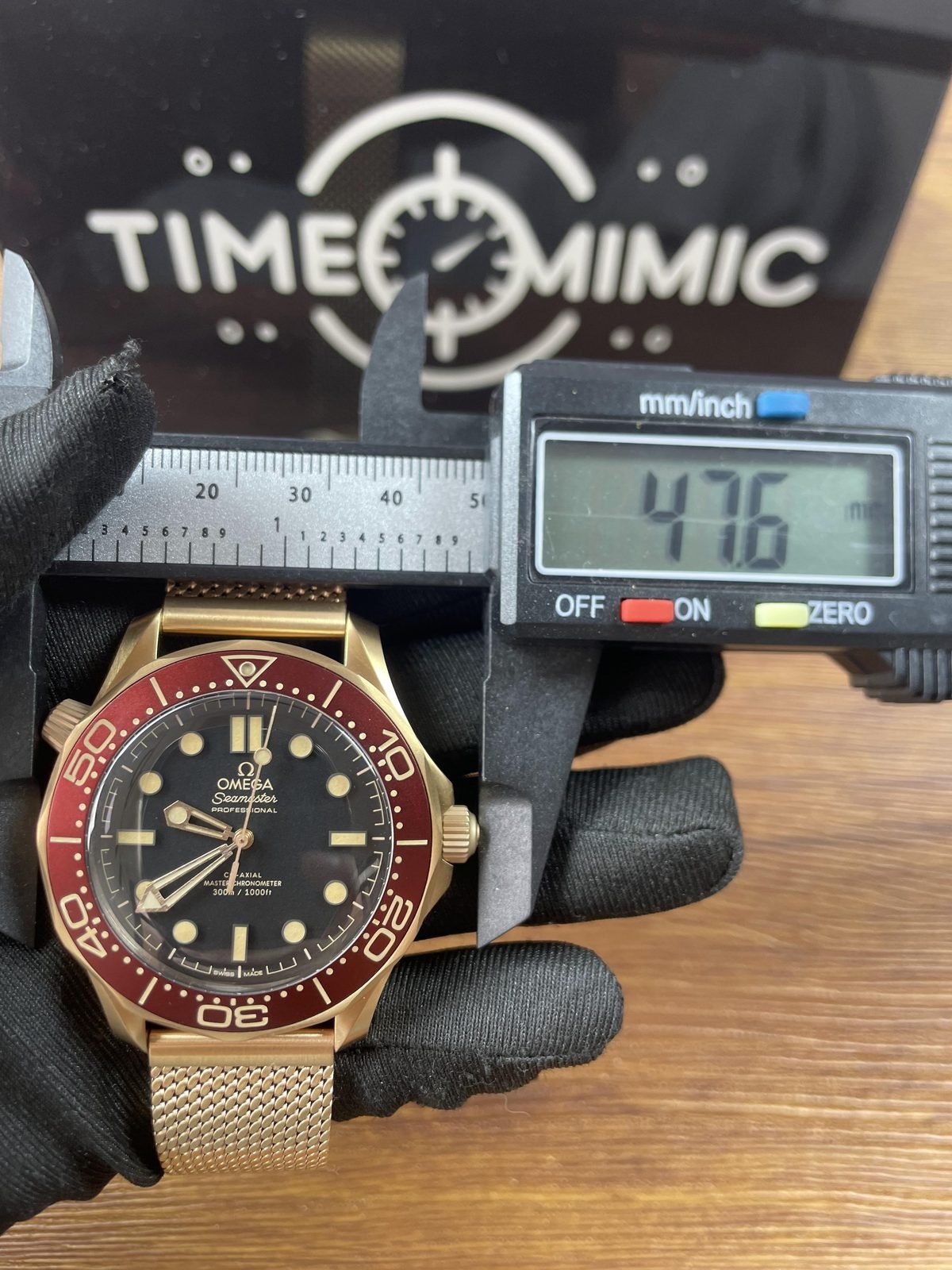Digital calliper displaying about 47.6 millimetres across outside valve to crown style span of warm tone Seamaster replica
