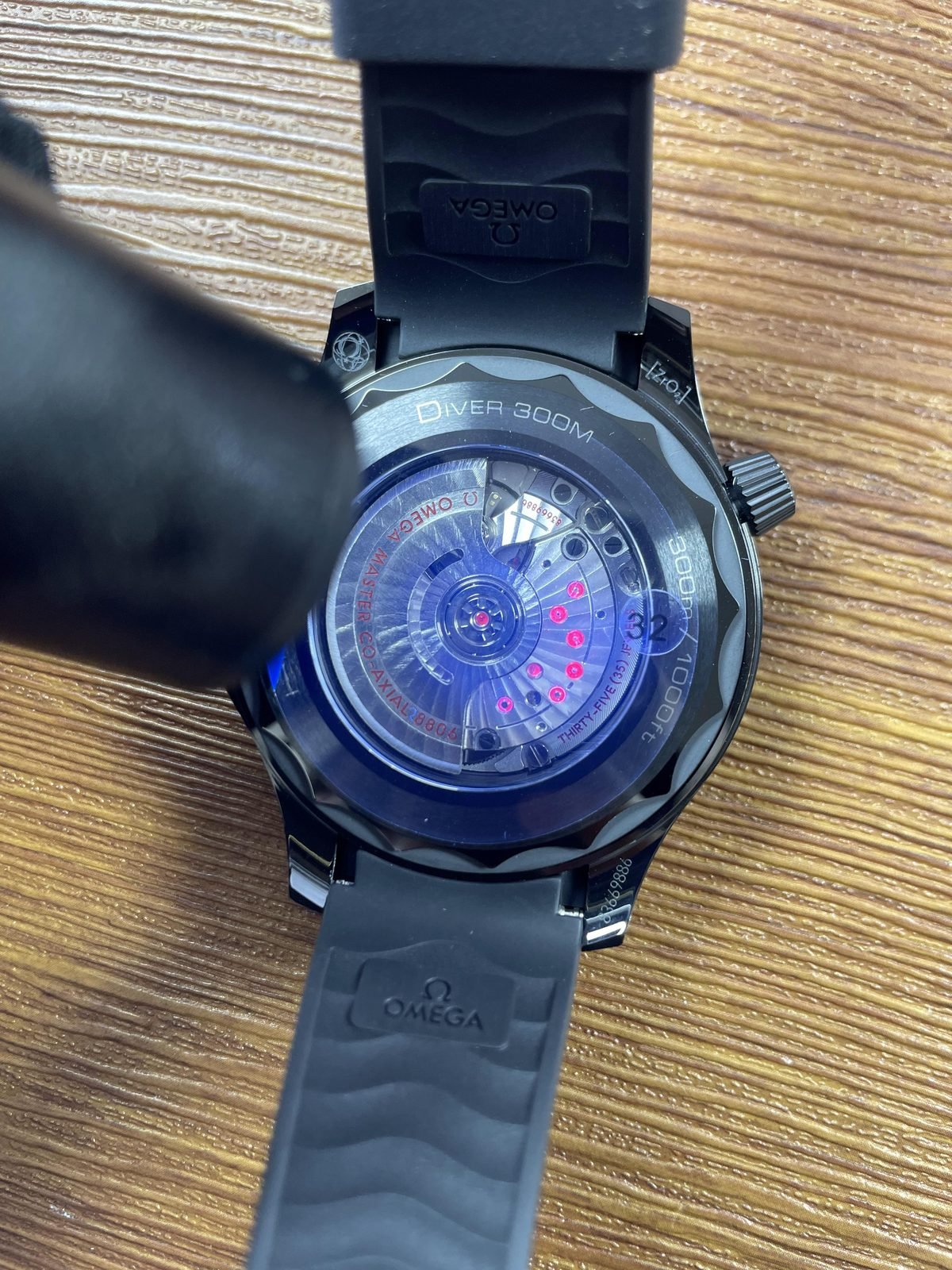 Decorated automatic looking movement under handheld light with 35 jewels style wording on Seamaster replica