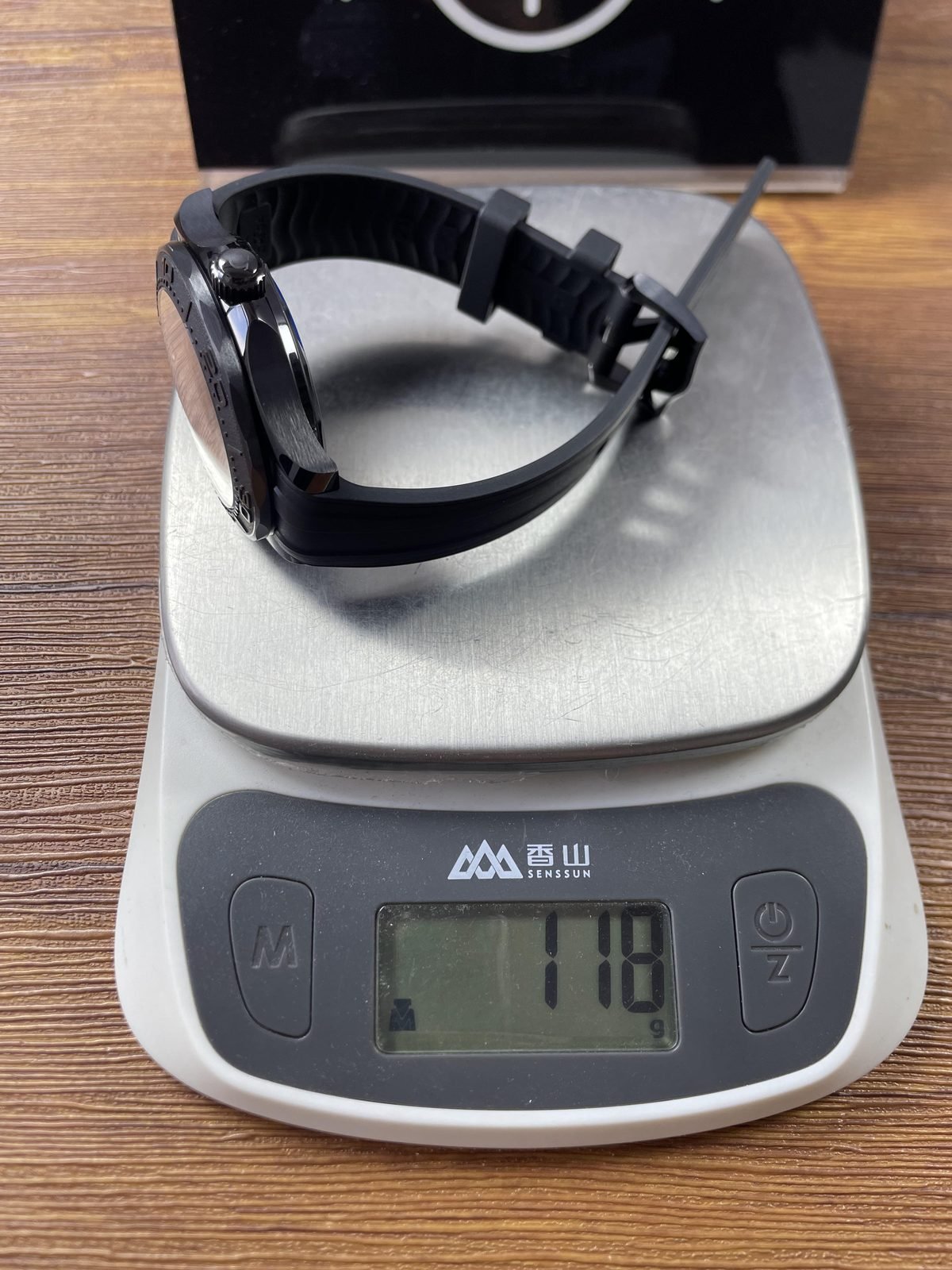 Black rubber strap Seamaster replica on scale displaying approximately 118 grams