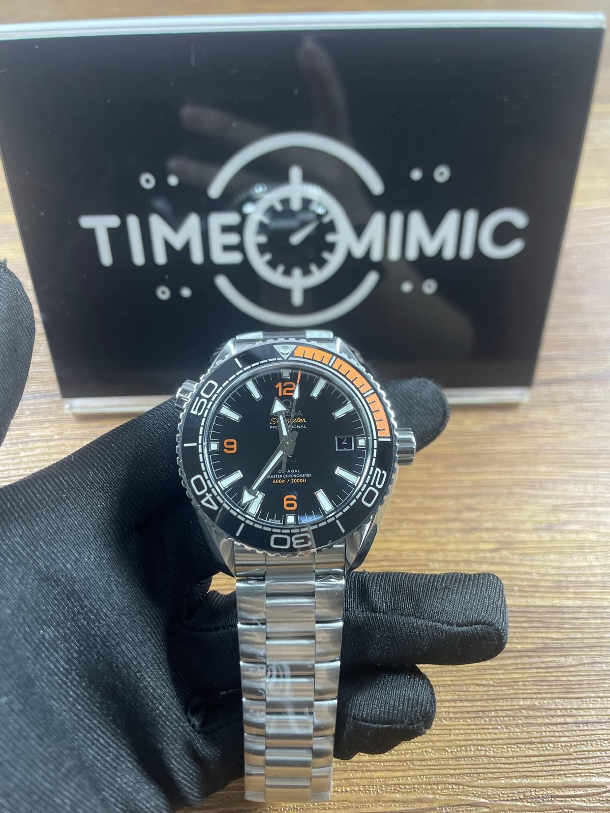 Black and orange Omega Planet Ocean 215.30.44.21.01.002 style replica on steel tone bracelet with date appearing as 4