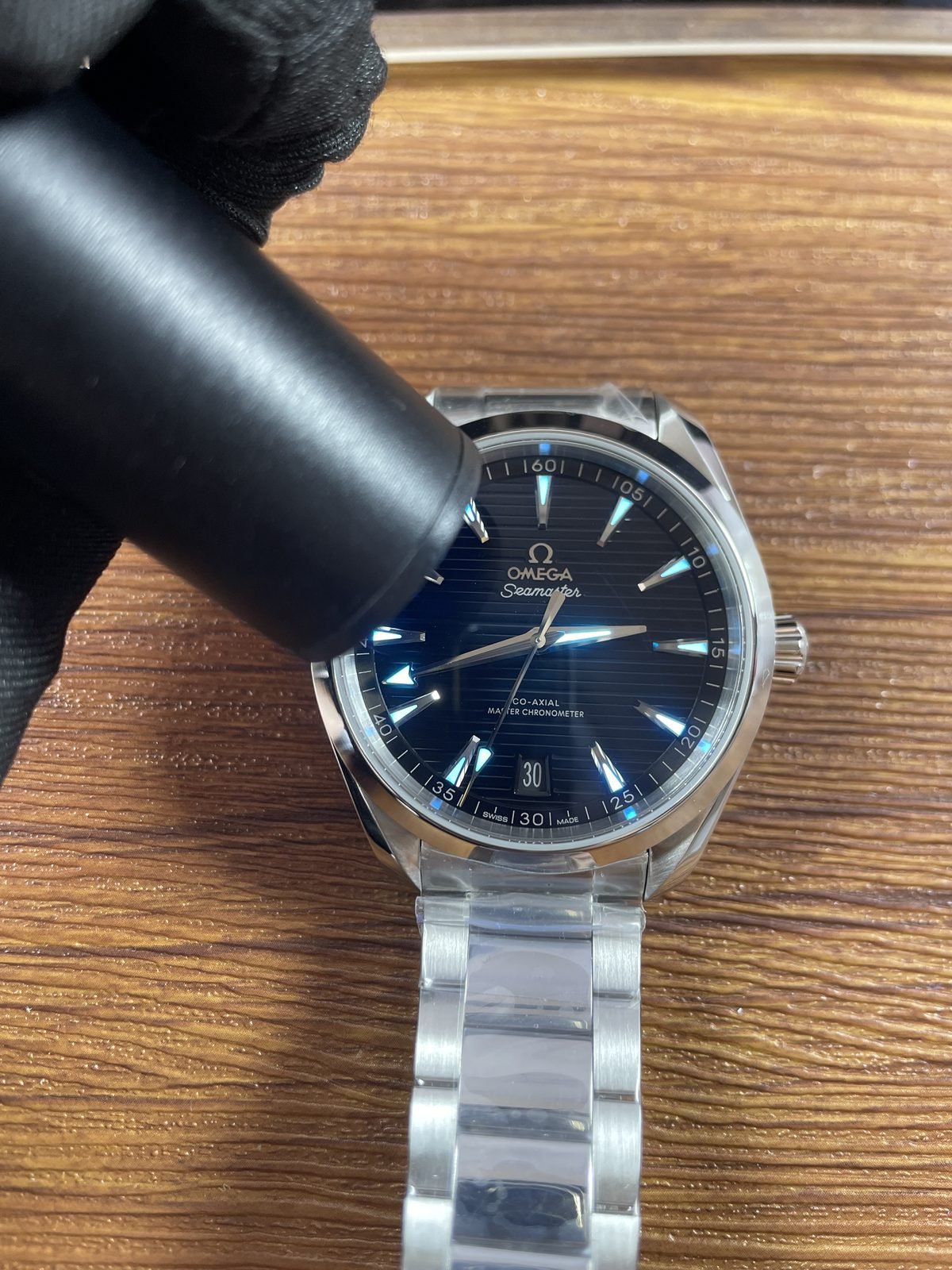 Hands and indexes of black Aqua Terra replica showing immediate blue cyan luminous style response under handheld light