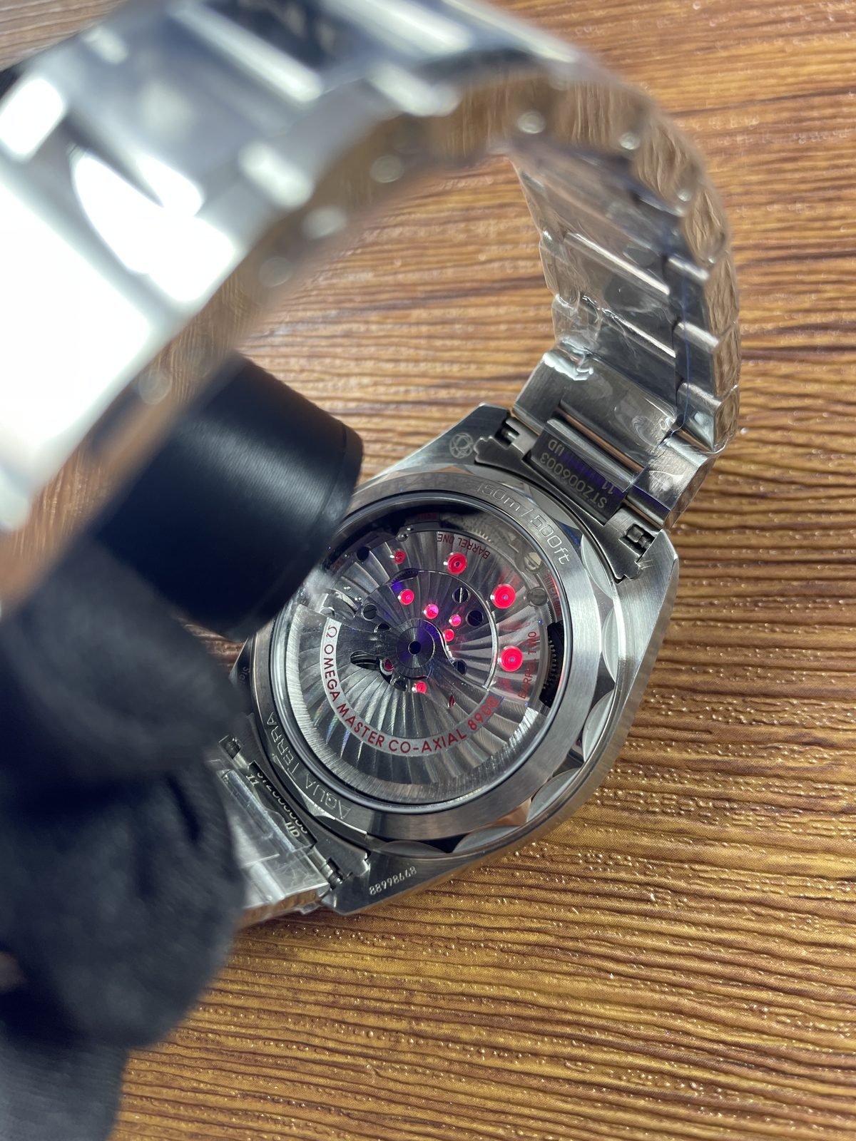 Illuminated transparent caseback closeup of Aqua Terra replica with barrel and 8900 style movement markings