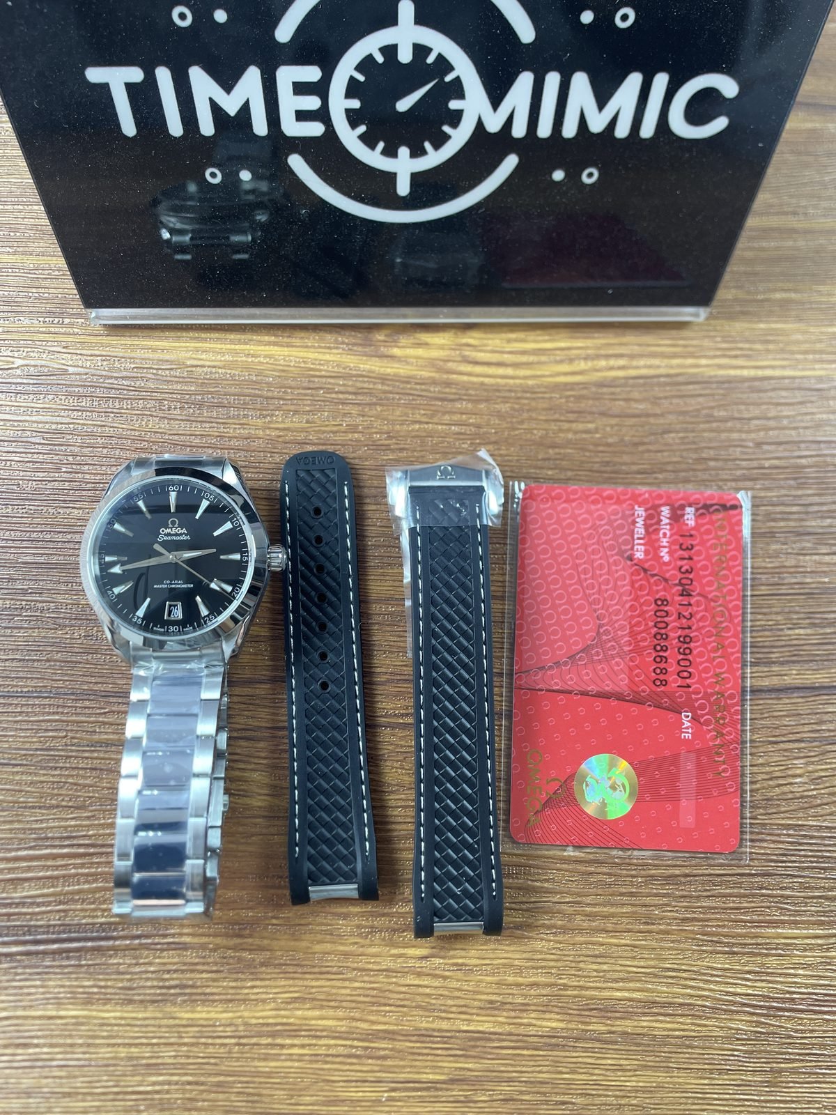 Horizontal stripe black dial Aqua Terra replica with steel tone bracelet loose black stitched strap pieces and mismatched 313 style red card
