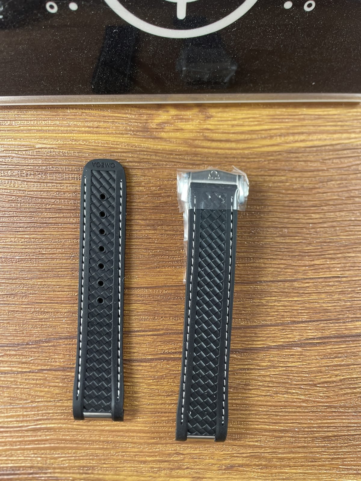 Two loose black Aqua Terra style strap sections with woven texture white stitching adjustment holes and clasp component