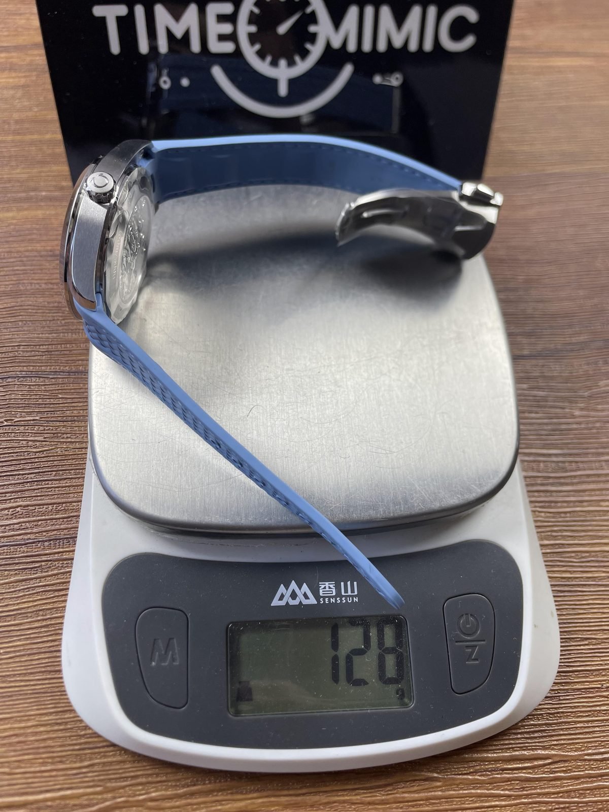 Summer Blue Worldtimer replica with strap and clasp on scale displaying about 128 grams